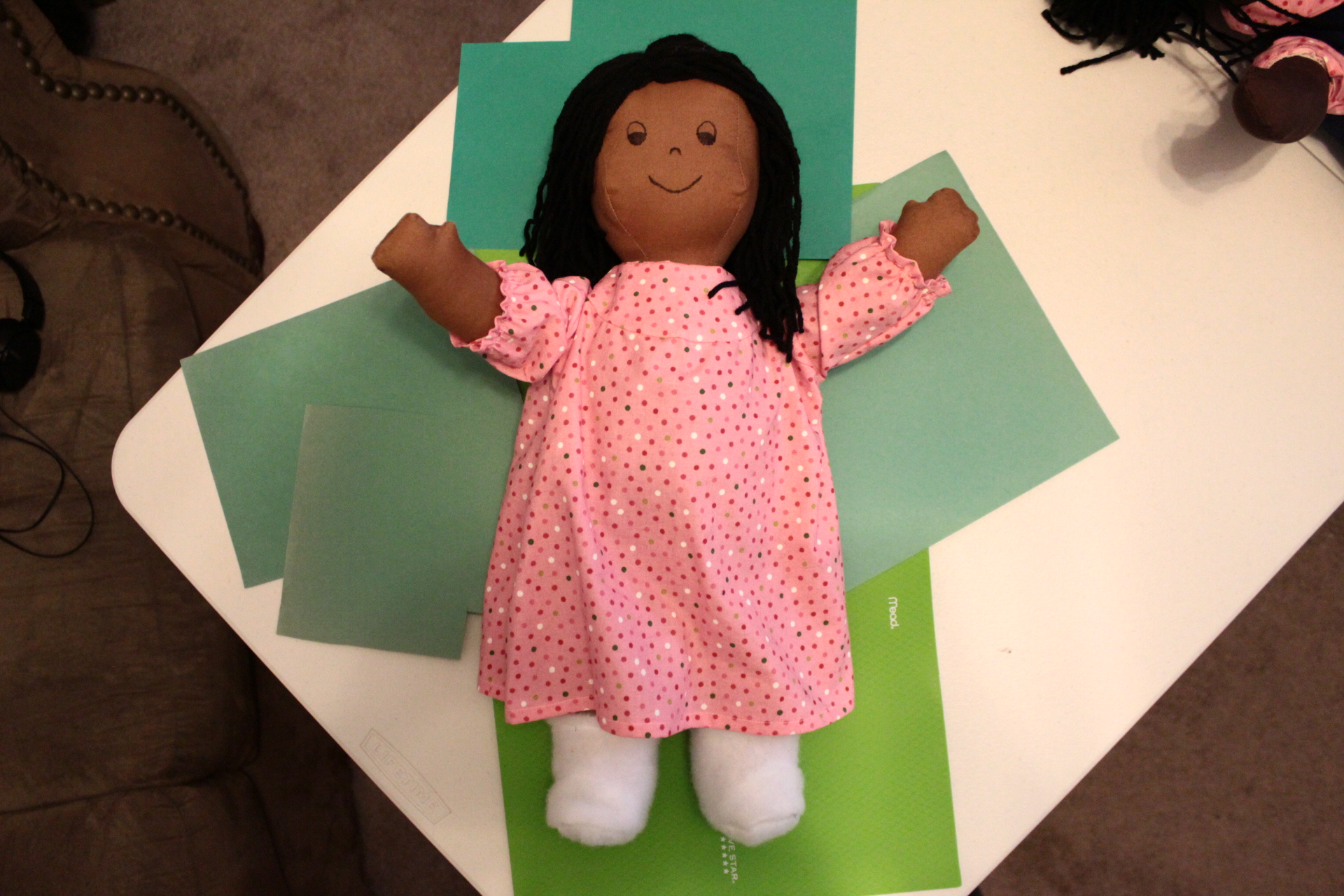 A doll sits on top of green construction paper